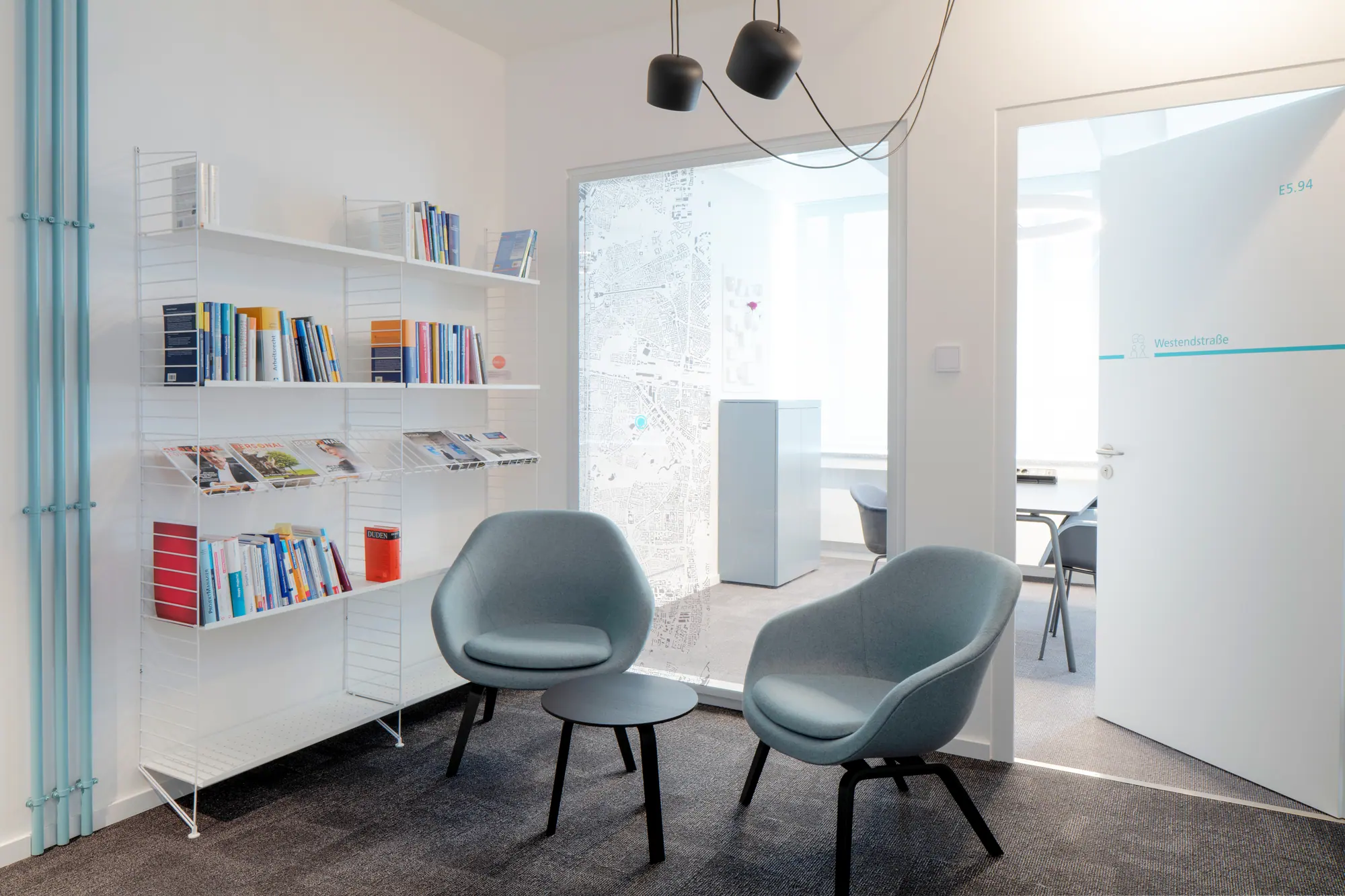 Sitzecke mit Sesseln und Bücherregal im Büro-Umbau Smartwork der Stadtwerke München