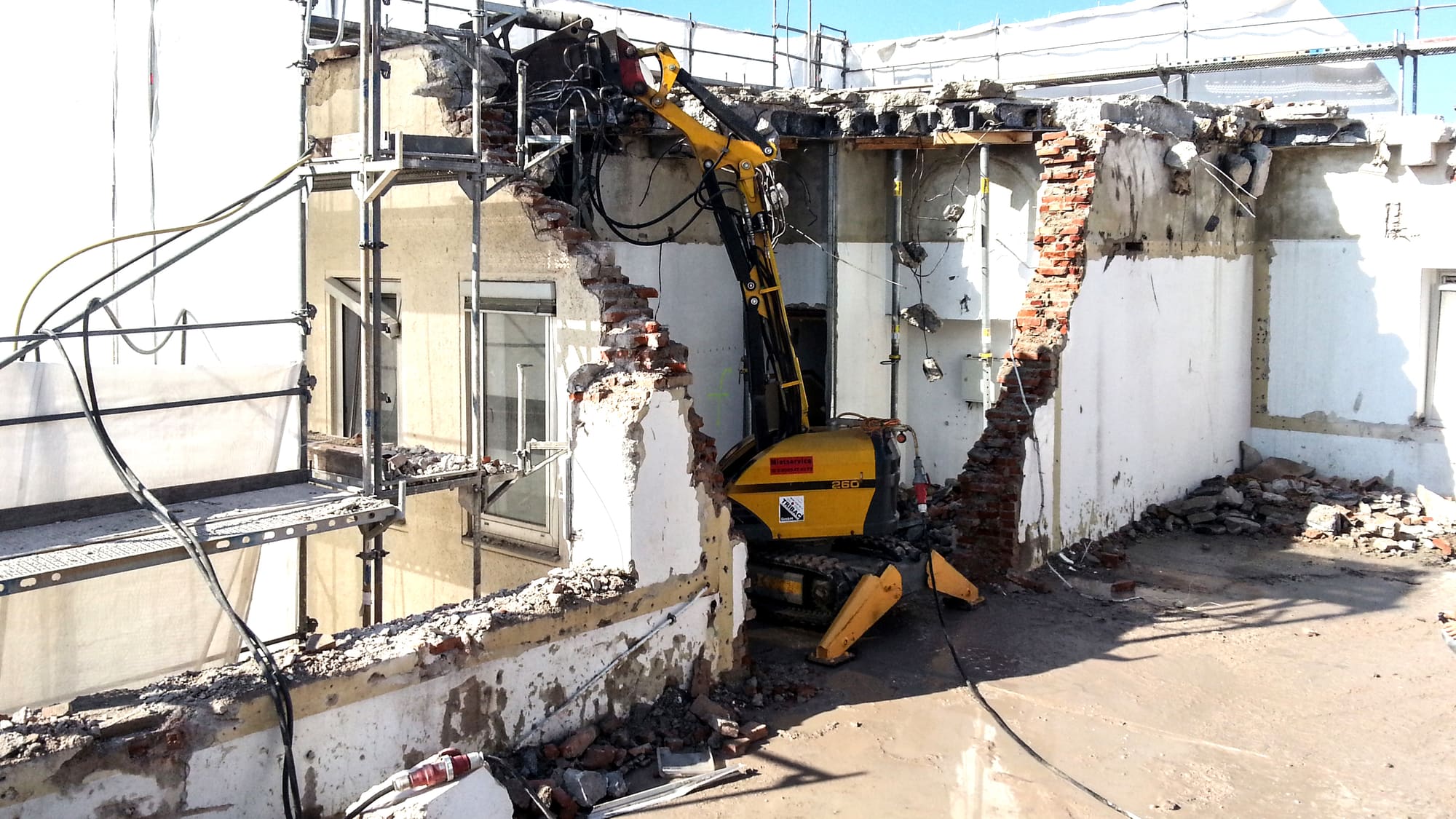Kleiner Abbruchbagger im geöffneten Gebäudeteil – Umspannwerk Schwabing: Rückbau der 10-kV-Anlage