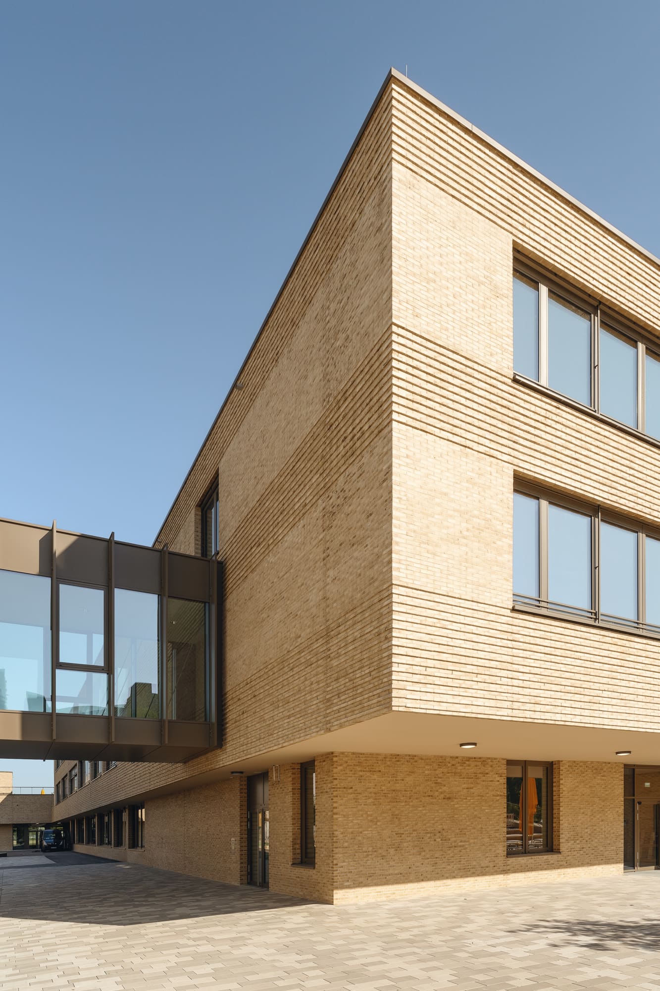 Gebäudeecke mit Klinkerfassade und Fensterbändern – Grundschule Haar: Erweiterung, Turnhalle und Tiefgarage
