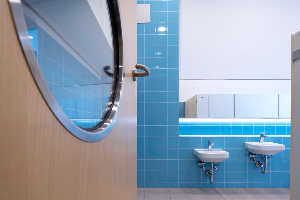 Rundes Fenster in einer Tür zum Sanitärbereich – Innenausbau eines Kindergartens in Germering