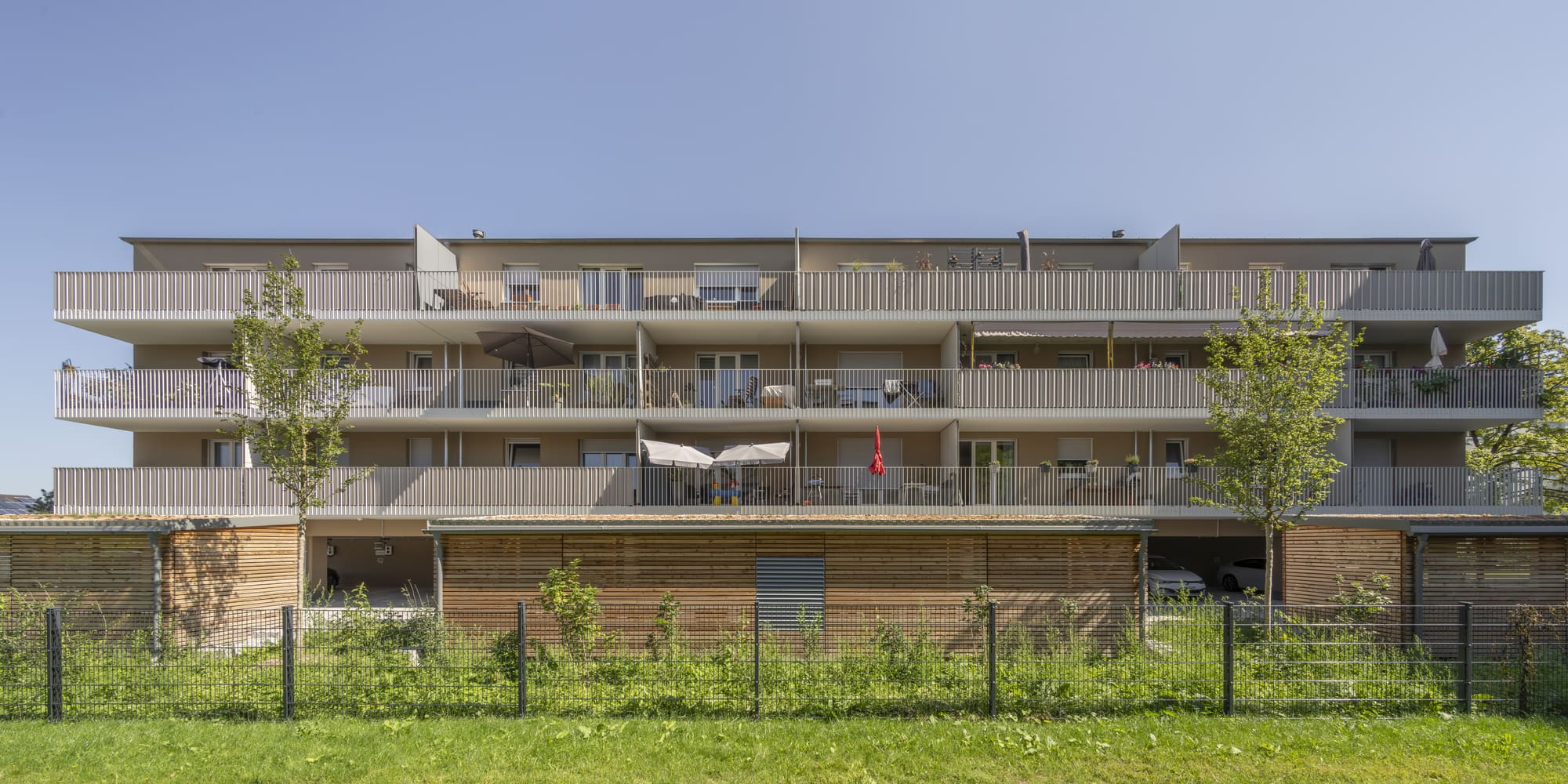 Wohngebäude mit durchlaufenden Balkonen und begrüntem Vorbereich – Nachverdichtung und Aufstockung in München